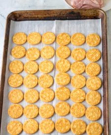 Ritz crackers laid out on a baking sheet face down.