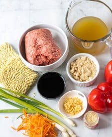 Ingredient shot of Slow Cooker Beef Ramen, carrots, scallions, sesame seeds, red bell pepper, garlic, brown sugar, soy sauce, chicken stock, ground beef and ramen noodles