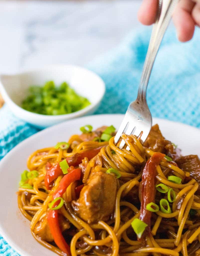 Pile of Slow Cooker Honey Garlic Chicken and Noodles with a fork taking out a bite.