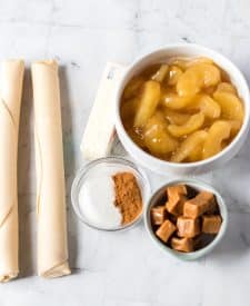 Ingredient shot of apple pie filling, caramels, pie dough, butter and cinnamon and sugar