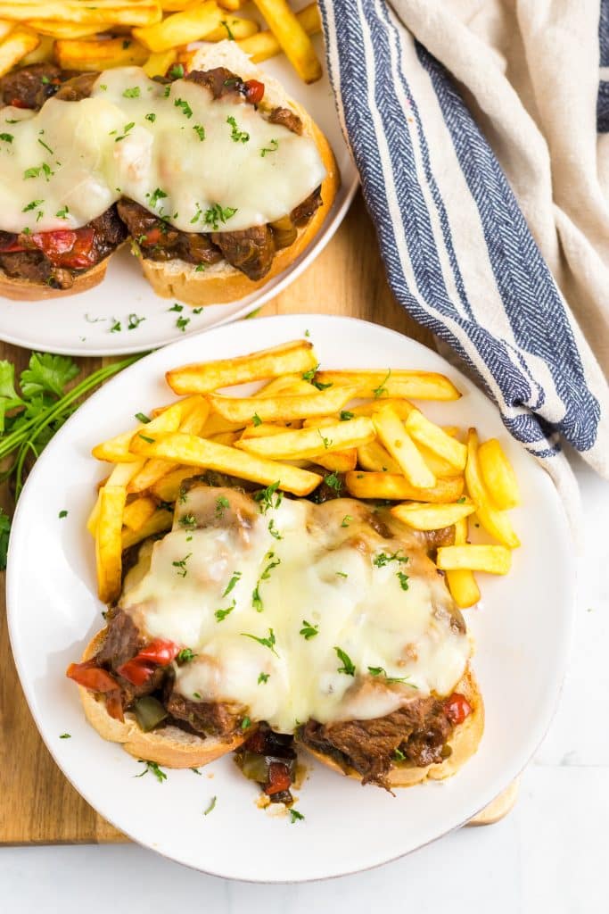 Slow Cooker Philly Cheesesteak Bites close up on a plate with melty cheese and fries
