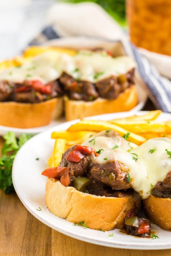 Slow Cooker Philly Cheesesteak Bites close up on a plate with melty cheese and fries