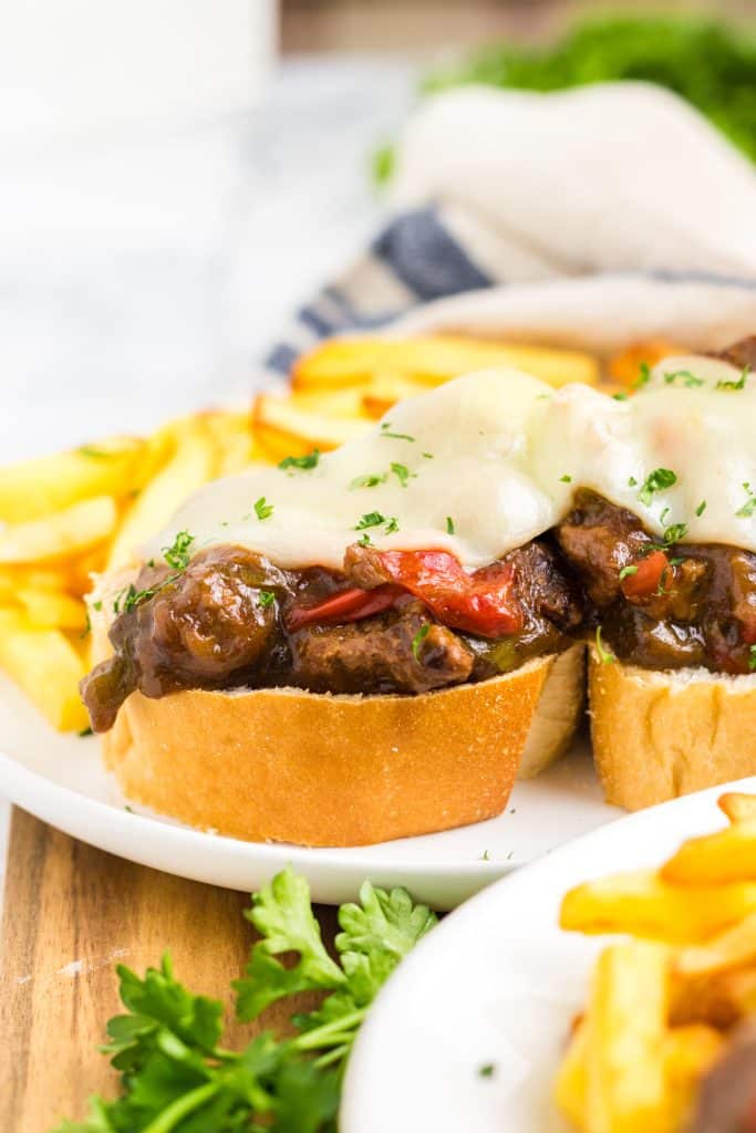 Slow Cooker Philly Cheesesteak Bites close up on a plate with melty cheese and fries