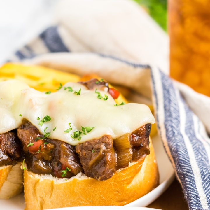 Slow Cooker Philly Cheesesteak Bites close up on a plate with melty cheese and fries