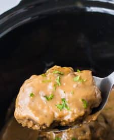 Slow Cooker Smothered Hamburgers cooked in slow cooker garnished with parsley in a spoon