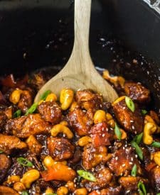 Slow Cooker Cashew Chicken in a slow cooker being spooned out