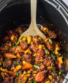 Slow Cooker Cashew Chicken in a slow cooker being spooned out