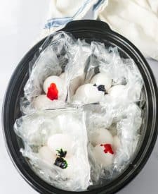 Slow Cooker Dyed Easter Eggs slow cooker shot with aluminum foil dividing the slow cooker into 4 sections, each section has a slow cooker liner and eggs with food coloring