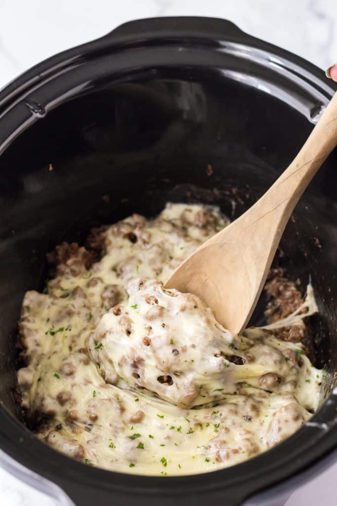 Slow Cooker French Dip Sloppy Joes in slow cooker with melty cheese being spooned out