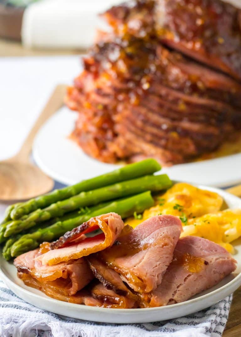 Slow Cooker Hot Honey Peach Glazed Ham plated with cheesy potatoes and asparagus