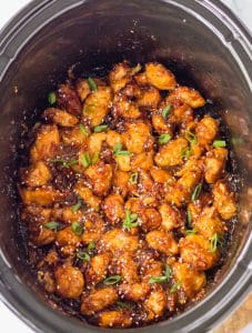 Slow Cooker Orange Chicken in slow cooker cooked with sesame seeds and scallions
