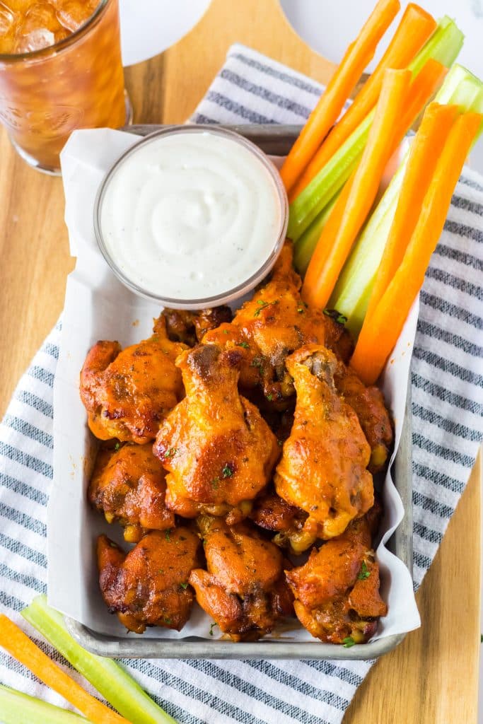Slow Cooker Buffalo Ranch Chicken Wings piled on a tray with veggies and ranch