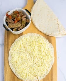 Slow Cooker Cheesesteak Quesadillas ingredients on tortilla
