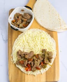 Slow Cooker Cheesesteak Quesadillas ingredients on tortilla