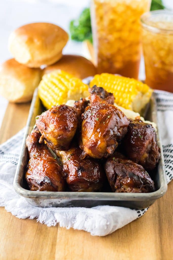 Slow Cooker Honey BBQ Drumsticks piled on a plate with mashed potatoes and corn