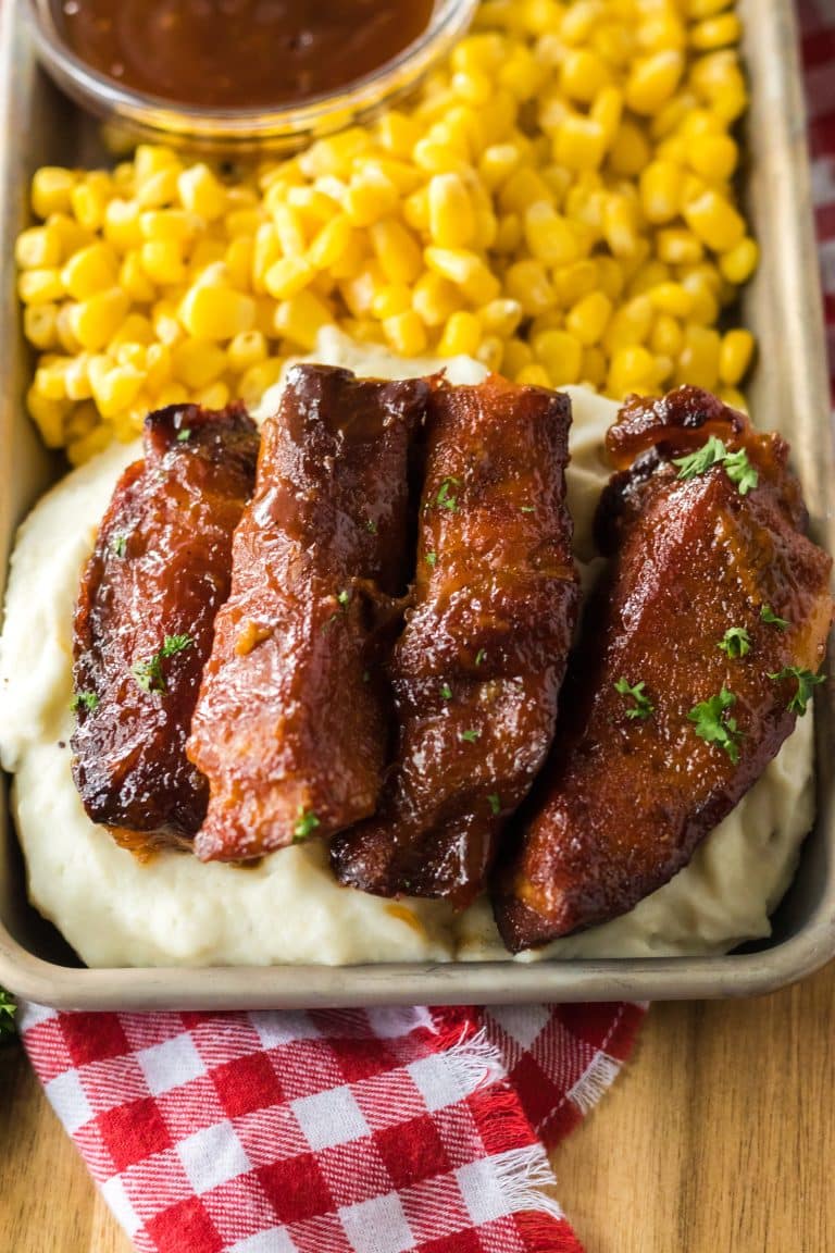 Slow Cooker Honey Peach Country Ribs piled on a plate with mashed potatoes and corn