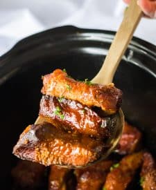 Slow Cooker Honey Peach Country Ribs being spooned out of slow cooker