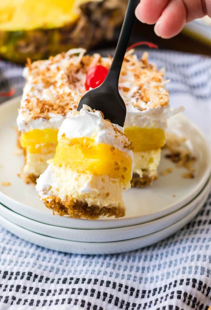 Pina Colada Cheesecake Bars sliced on a plate with a bite on the fork