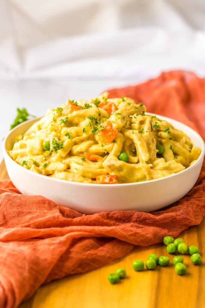 Creamy slow cooker chicken and noodles in a bowl with peas and carrots