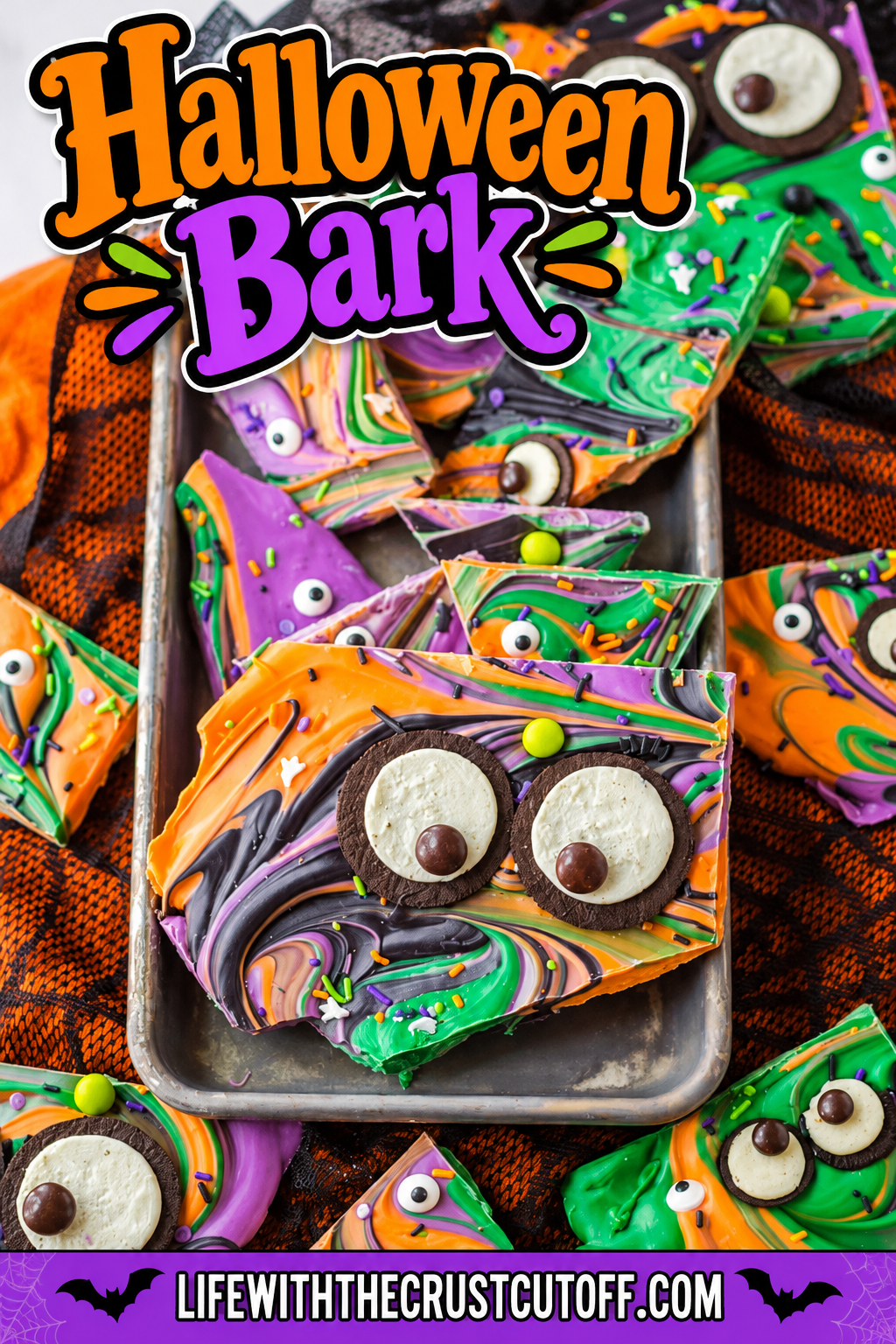 Colorful Halloween Bark with orange, purple, green, and black swirls decorated with candy eyes, cookies, and Halloween sprinkles.