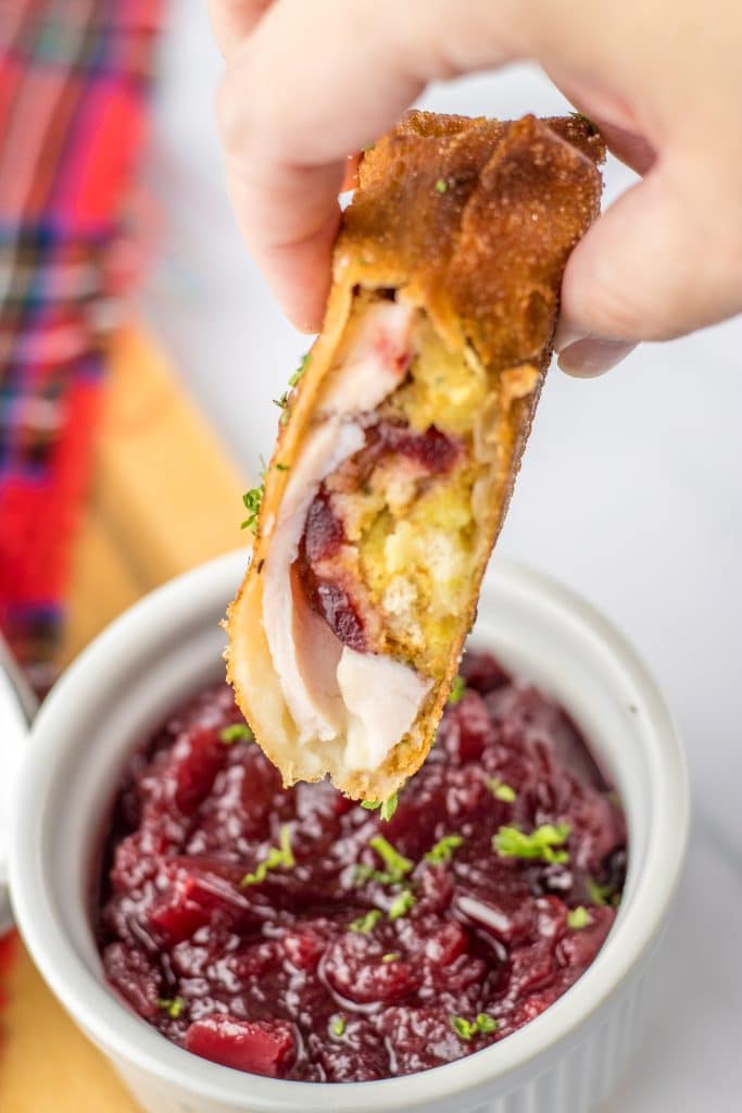 Thanksgiving Egg Rolls being dipped in cranberry sauce