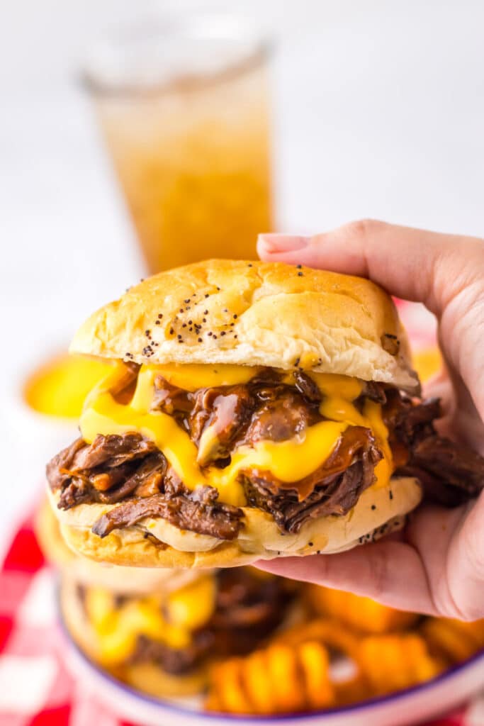 Slow Cooker Arbys Roast Beef and Cheddar Sandwiches in hand