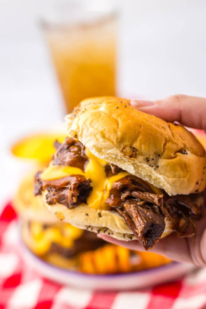 Slow Cooker Arbys Roast Beef and Cheddar Sandwiches in hand