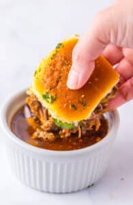 Slow Cooker Birria Sliders being dipped