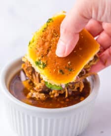 Slow Cooker Birria Sliders being dipped