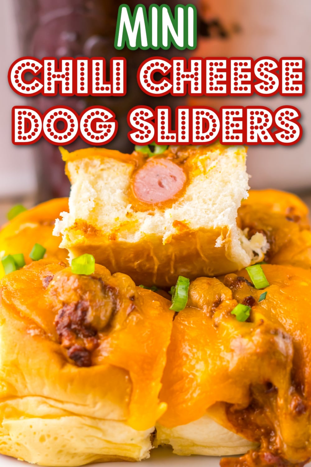 Mini chili cheese dog sliders on a white plate topped with melted cheese and chili sauce, perfect for party appetizers and game day snacks