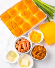 Mini chili cheese dog sliders baked on Hawaiian rolls with hot dogs, chili, melted cheddar cheese, and toppings, perfect for an easy weeknight dinner or game day appetizer.
