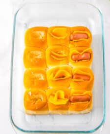 Mini chili cheese dog sliders baked on Hawaiian rolls with hot dogs, chili, melted cheddar cheese, and toppings, perfect for an easy weeknight dinner or game day appetizer.