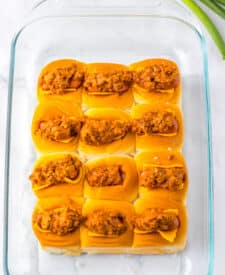 Mini chili cheese dog sliders baked on Hawaiian rolls with hot dogs, chili, melted cheddar cheese, and toppings, perfect for an easy weeknight dinner or game day appetizer.