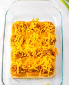 Mini chili cheese dog sliders baked on Hawaiian rolls with hot dogs, chili, melted cheddar cheese, and toppings, perfect for an easy weeknight dinner or game day appetizer.