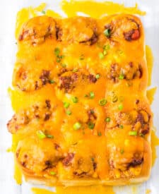 Mini chili cheese dog sliders baked on Hawaiian rolls with hot dogs, chili, melted cheddar cheese, and toppings, perfect for an easy weeknight dinner or game day appetizer.