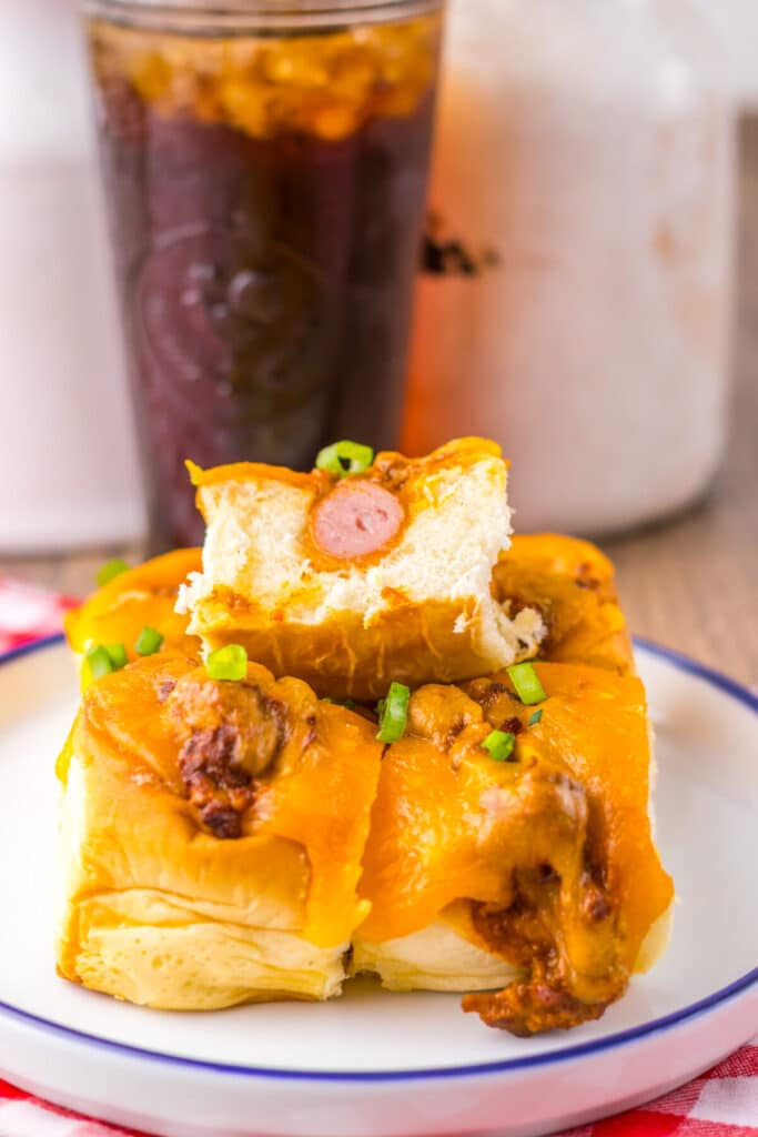 Mini chili cheese dog sliders baked on Hawaiian rolls with hot dogs, chili, melted cheddar cheese, and toppings, perfect for an easy weeknight dinner or game day appetizer.