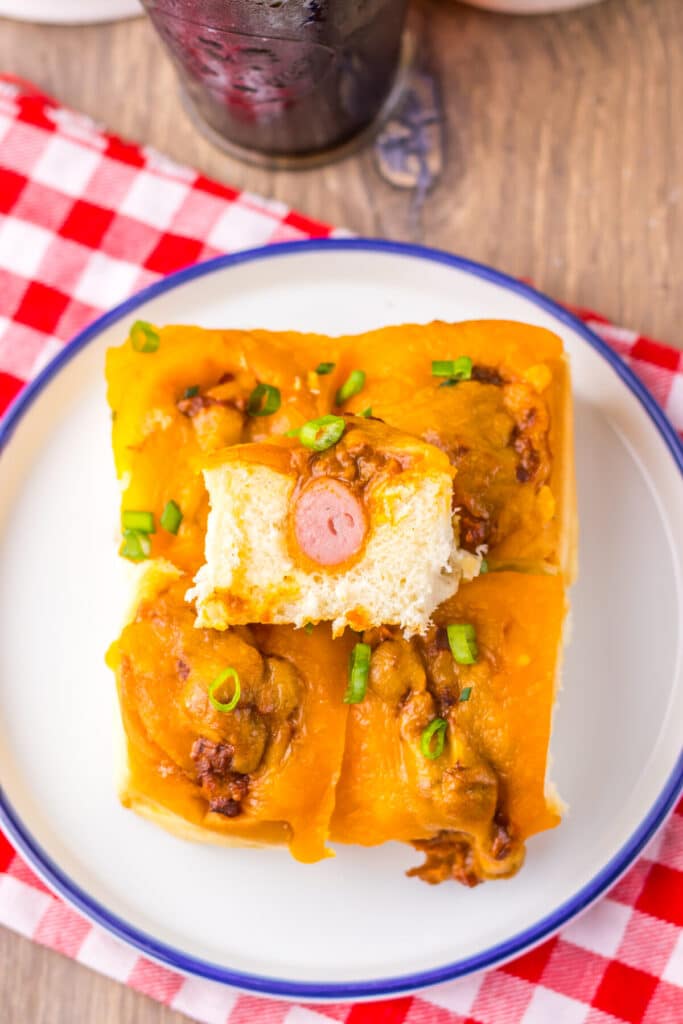 Mini chili cheese dog sliders baked on Hawaiian rolls with hot dogs, chili, melted cheddar cheese, and toppings, perfect for an easy weeknight dinner or game day appetizer.