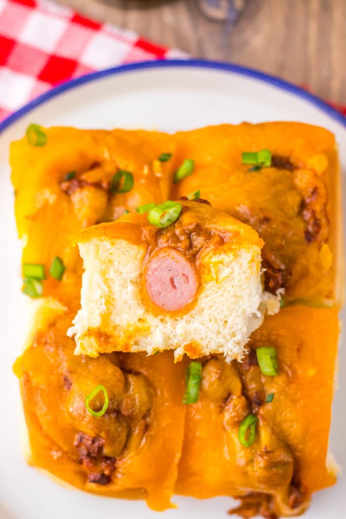 Mini chili cheese dog sliders baked on Hawaiian rolls with hot dogs, chili, melted cheddar cheese, and toppings, perfect for an easy weeknight dinner or game day appetizer.