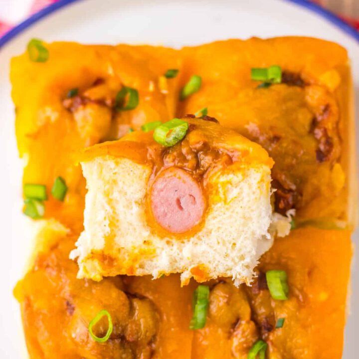 Mini chili cheese dog sliders baked on Hawaiian rolls with hot dogs, chili, melted cheddar cheese, and toppings, perfect for an easy weeknight dinner or game day appetizer.