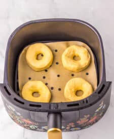 Air fryer basket with raw biscuit doughnut shapes before cooking
