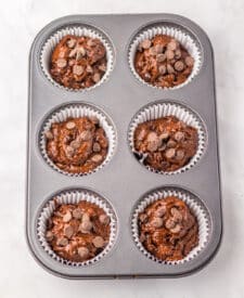 Jumbo Costco-style double chocolate muffins with melty chocolate chips on top, baked at home and cooling in liners on a wire rack.