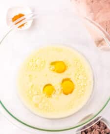 Jumbo Costco-style double chocolate muffins with melty chocolate chips on top, baked at home and cooling in liners on a wire rack.