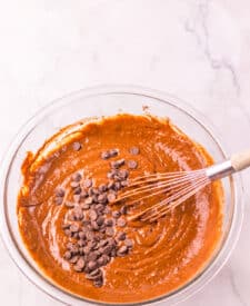 Jumbo Costco-style double chocolate muffins with melty chocolate chips on top, baked at home and cooling in liners on a wire rack.