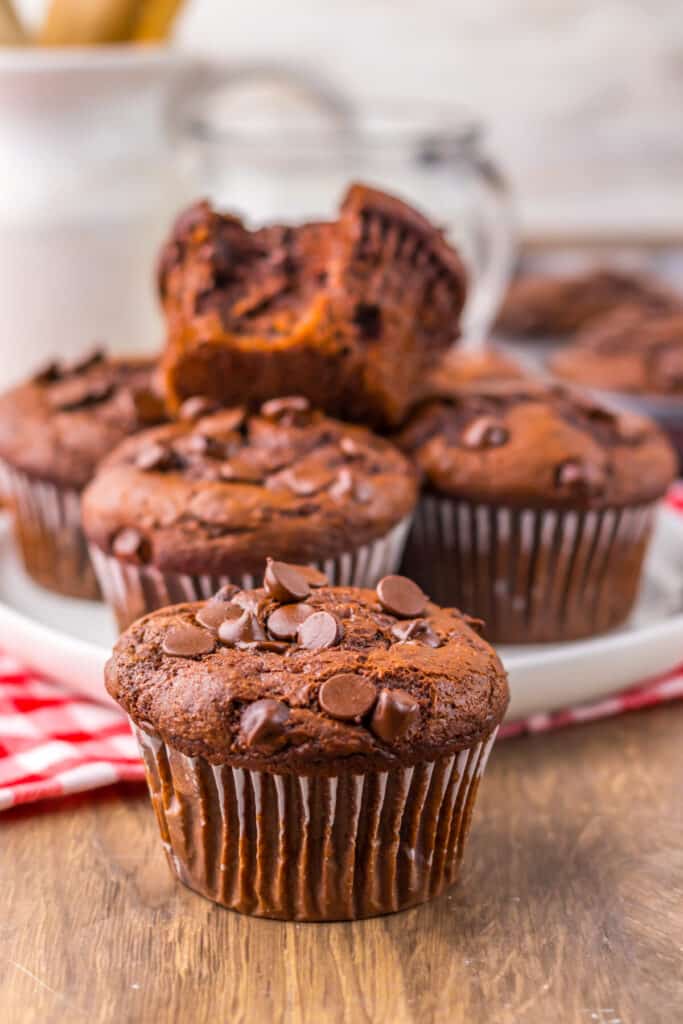 Jumbo Costco-style double chocolate muffins with melty chocolate chips on top, baked at home and cooling in liners on a wire rack.