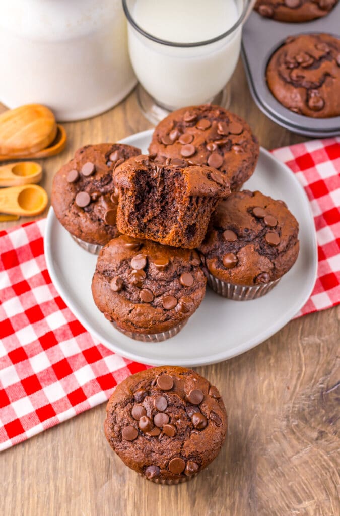 Jumbo Costco-style double chocolate muffins with melty chocolate chips on top, baked at home and cooling in liners on a wire rack.