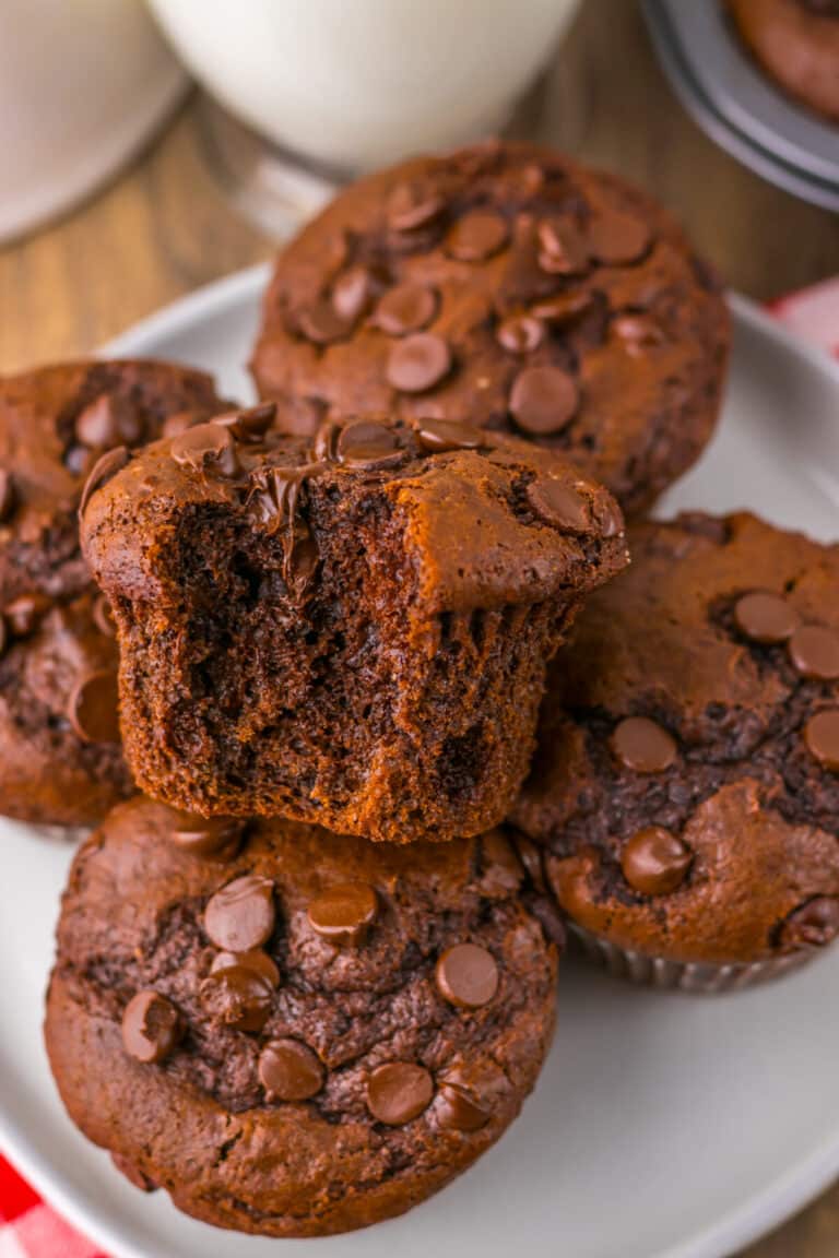 Jumbo Costco-style double chocolate muffins with melty chocolate chips on top, baked at home and cooling in liners on a wire rack.