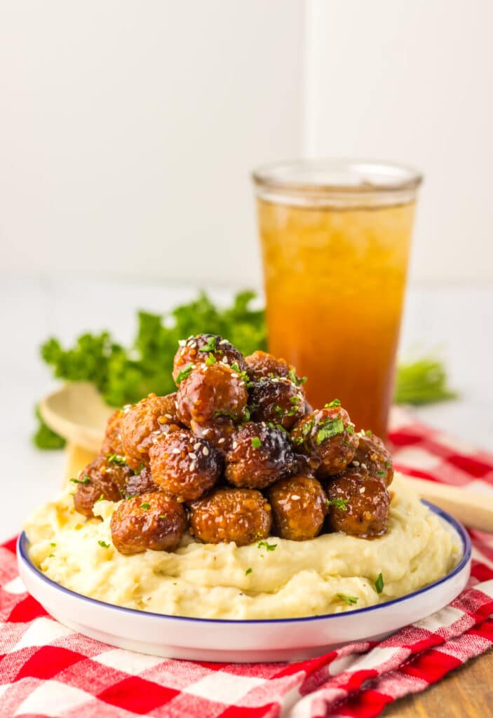 “Baked honey garlic meatballs in a glossy, sticky sauce garnished with sesame seeds and green onions”