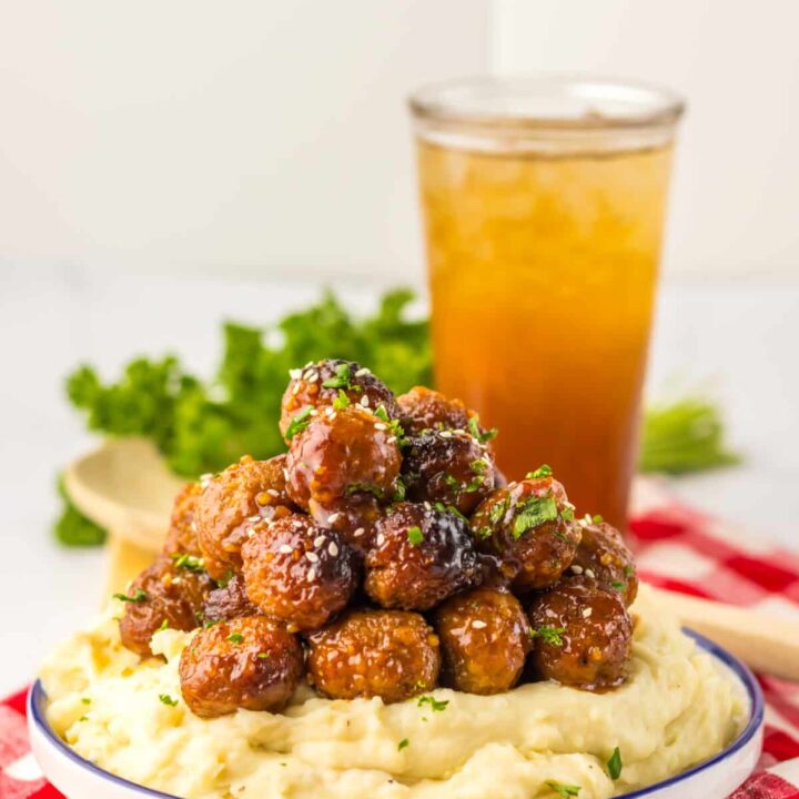 “Baked honey garlic meatballs in a glossy, sticky sauce garnished with sesame seeds and green onions”