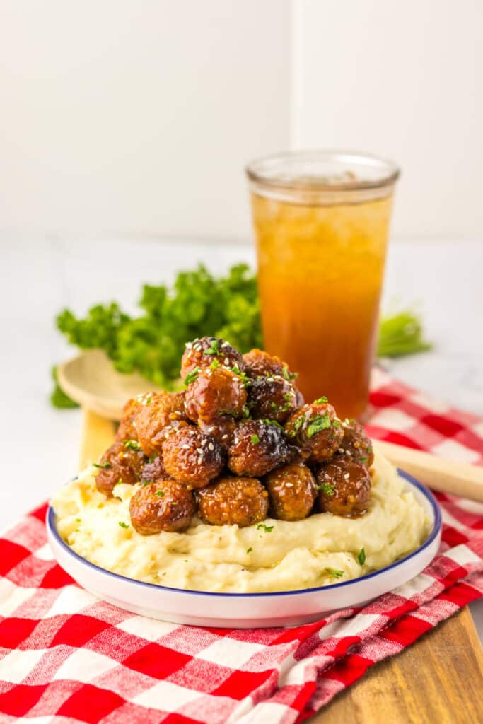 “Baked honey garlic meatballs in a glossy, sticky sauce garnished with sesame seeds and green onions”