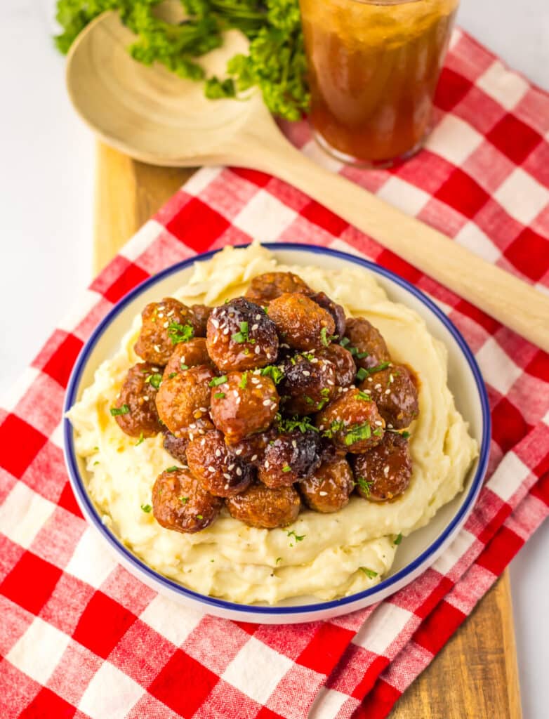 “Baked honey garlic meatballs in a glossy, sticky sauce garnished with sesame seeds and green onions”